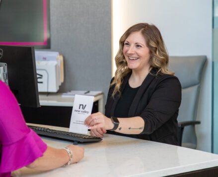 Bank teller smiling and assisting a customer at the counter.