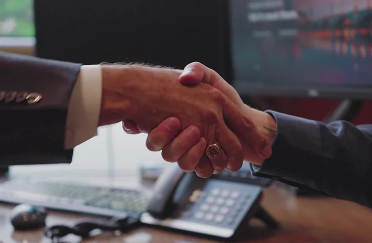 New Valley Bank employee shakes a customer's hand at an in-person meeting.